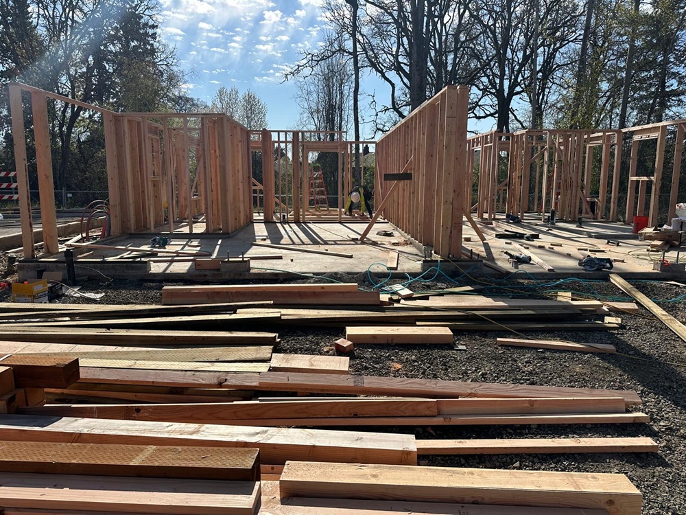 Framing Services by ABM General Construction, showing new wall framing in progress on a slab foundation with stud walls laid out for rooms on a residential build site.
