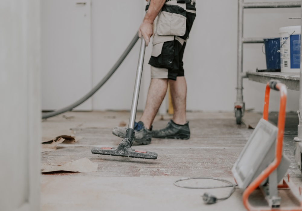 Professional Cleaning & Post-Construction Services by ABM General Construction LLC, showing a worker vacuuming construction dust and debris from a floor during post-construction cleanup.